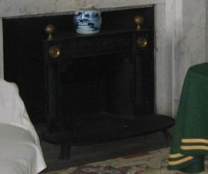 An iron Franklin style stove inserted into a white marble fireplace.