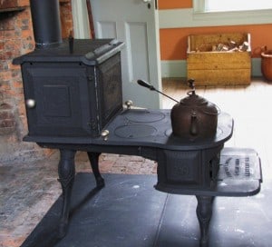 Stepped iron cookstove in front of a fireplace seen from the side
