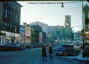 two people walking with buildings and cars in the background