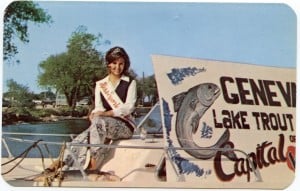 Woman on a boat next to a sign with a fish on it and Geneva: Lake Trout Capital of the World