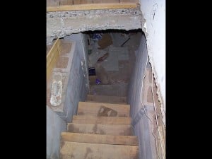 Old stairs leading to a messy basement floor.