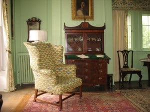 Light green painted room with antique furniture and needle pointed wing chair.