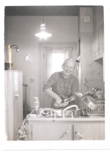 A woman washing dishes in a 1950s kitchen.