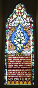 A stained glass window with lilies and the names and death dates of 10 Sunday School children who died of diphtheria.
