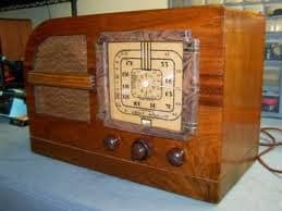 Old-fashioned wooden radio with three dials and a built-in speaker.