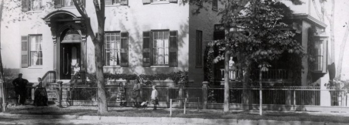 A man, woman and five girls stand in front of the Prouty-Chew House. One girl stands on a side porch and another on the front stoop.