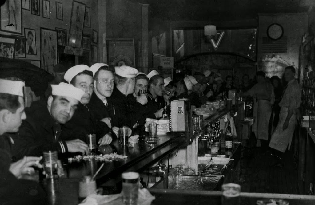 Sailors lined up along a bar.