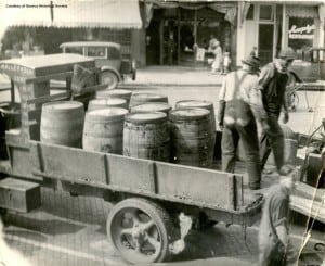 Men standing in a wagon full of beer barrels.