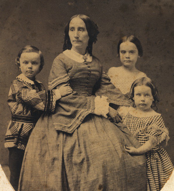 woman-seated-surrounded-by-3-children