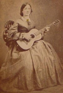 Sepia colored photograph of a young woman with a parlor guiltar