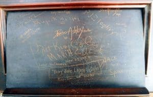 Music holder from the front piece of an upright piano with signatures from musicians who played at Club 86 in the 1940s and 1950s. Nat King Cole's signature is in the middle.