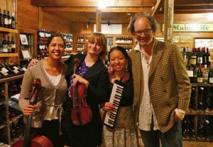 three women with instruments standing with a man