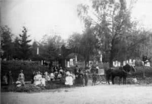 group of people with a horse and carriage standing outside a cemetery