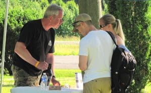 man serving a beverage to two people