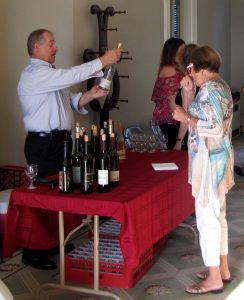 people standing around a table with wine bottles and glasses 