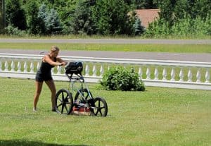 girl pushing a machine in a front yard