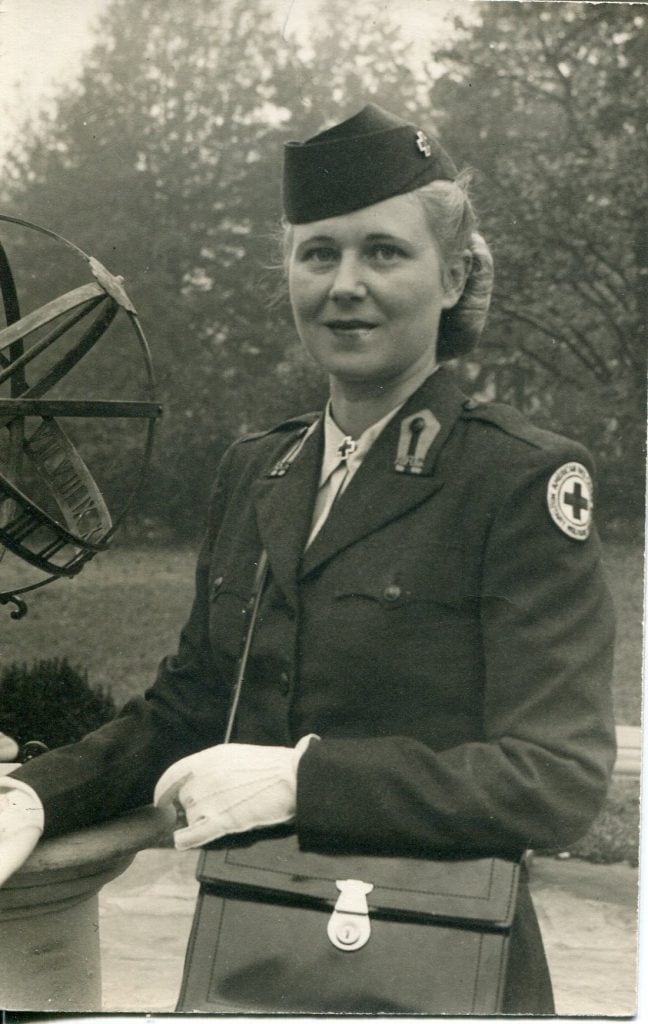 A woman in a red cross military-style uniform and cap.