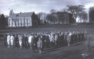 men standing in several rows with buildings in the background