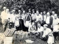 men-standing-in-an-orchard-with-boxes-of-apples