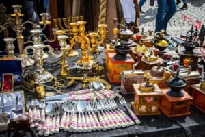 Antique candlebras, flatware and coffee grinders on a table.