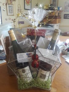 gift basket filled with wine, tickets and an ornament