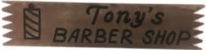 Handmade wooden sign with a barber pole and “Tony’s Barber Shop” painted on it.