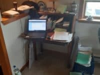small desk with lap top and folders surround by a water bottle, folders, and notebooks