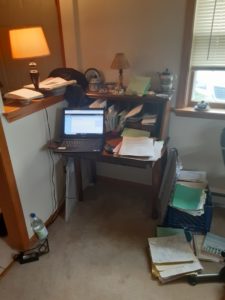 small desk with lap top and folders surround by a water bottle, folders, and notebooks