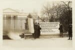 women with banners and a fire in a urn stand outside the White House