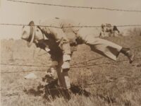 a man climbing over a barbed wire fence