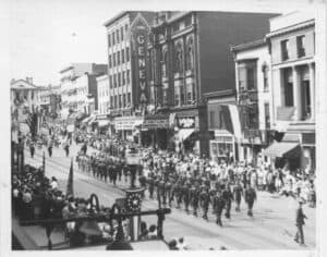 Soldiers marching down a dowtown street.  
