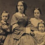 Three-quarter length portrait of a woman in a wide-sleeved dress with full skirts. There is a boy on her right and two girls on her left.
