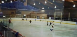 Girls of various ages ice skating on an indoor ice skating rink