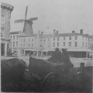 A wagon with a downtown intersection and grist mill in the foreground