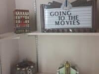 Three theater models and a sign "Going to the Movies" sitting on shelves.