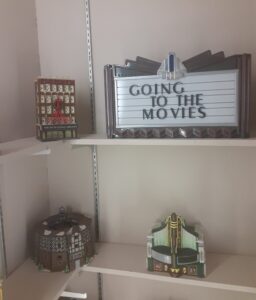 Three theater models and a sign "Going to the Movies" sitting on shelves.