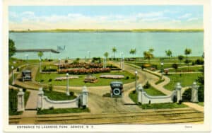 Postcard image of a car driving into a manicured lakeside park