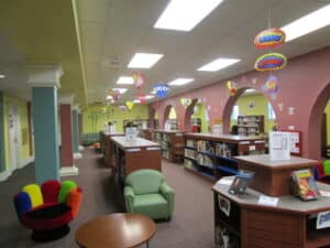 Brightly colored room with books shelves, tables and chairs.