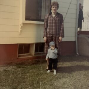 woman and child standing along side a house