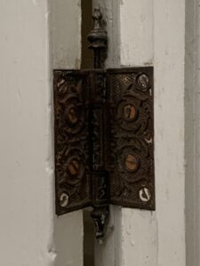 Close-up photo of a iron door hinge in the Housman home