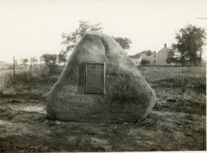 larger boulder with a plaque in a a field