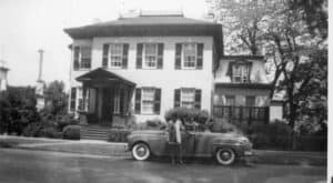two people and car in front of a multi-story house
