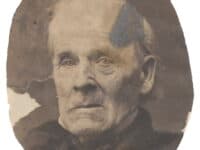 Portrait of the head and neck of an elderly white man wearing a cravat and coat.