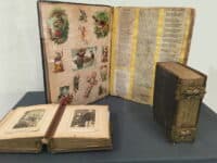 A display showing an open historic scrapbook and photo album.