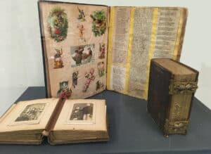 A display of an open historic scrapbook and photo album.