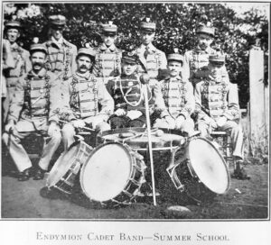men in uniform sitting in front of drums with men standing behind them
