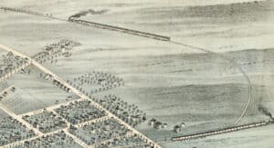 Birdseye view drawing of the edge of a town showing houses on streets bordered by fields and a train line.