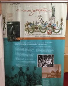Vertical vinyl banner with an image of the statue of libertu, text and group photoso in it.