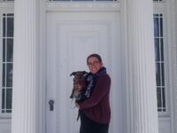 Woman with a dog in her arms standing at the front door of Rose Hill Mansion