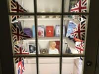 View of a cabinet of shelves full of books and mugs surrounded by decorative Union Jack flags.